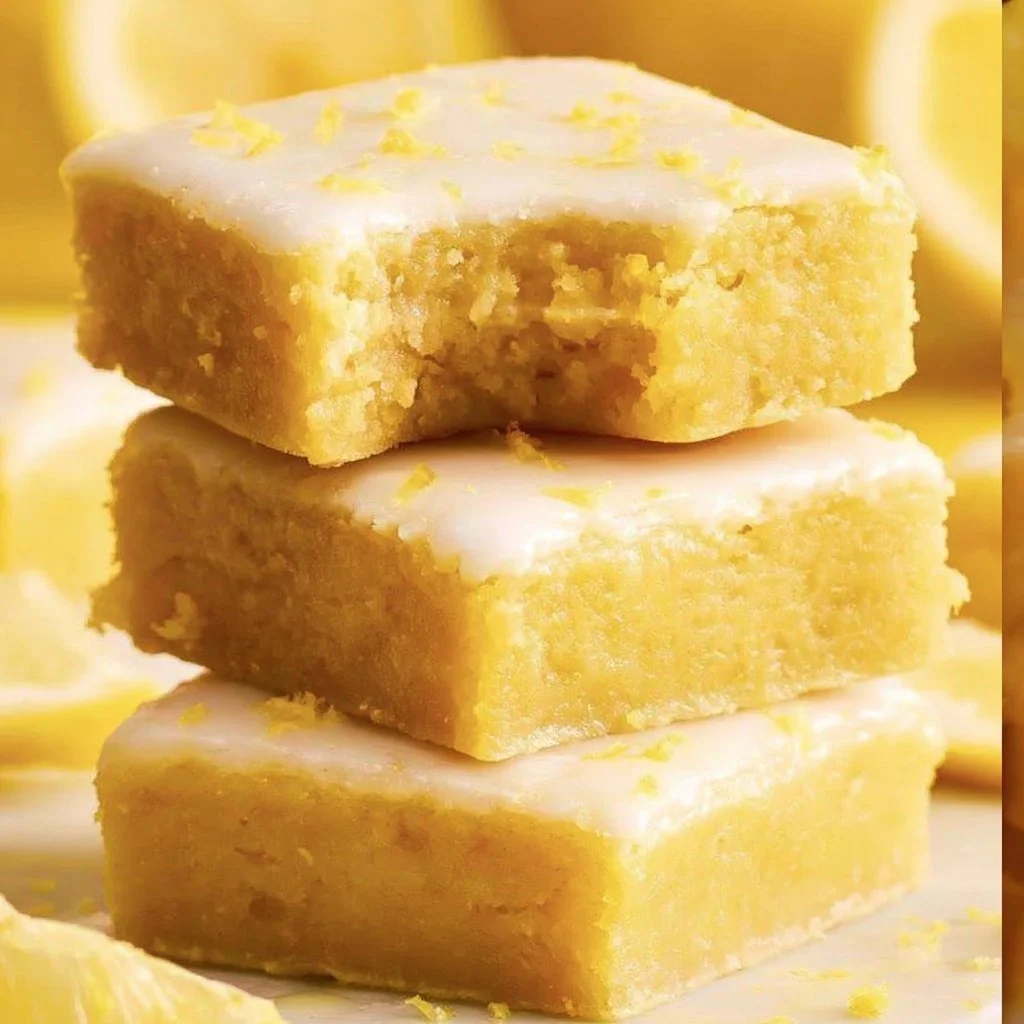 Freshly baked lemon brownies on a white plate garnished with lemon zest.